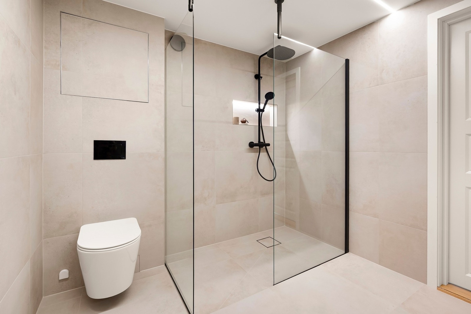 Videre inneholder badet vegghengt toalett og stor dusjnisje med skillevegg i herdet glass. Galleribilde