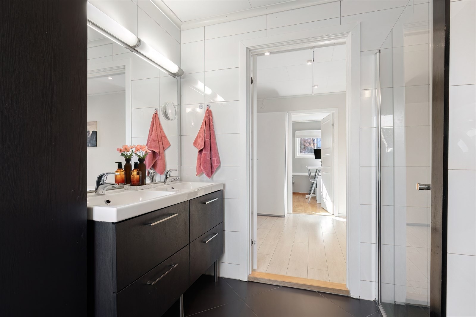 Praktisk innredet bad med dobbelvask, dusj, vegghengt toalett og vaskeromnisje. Galleribilde