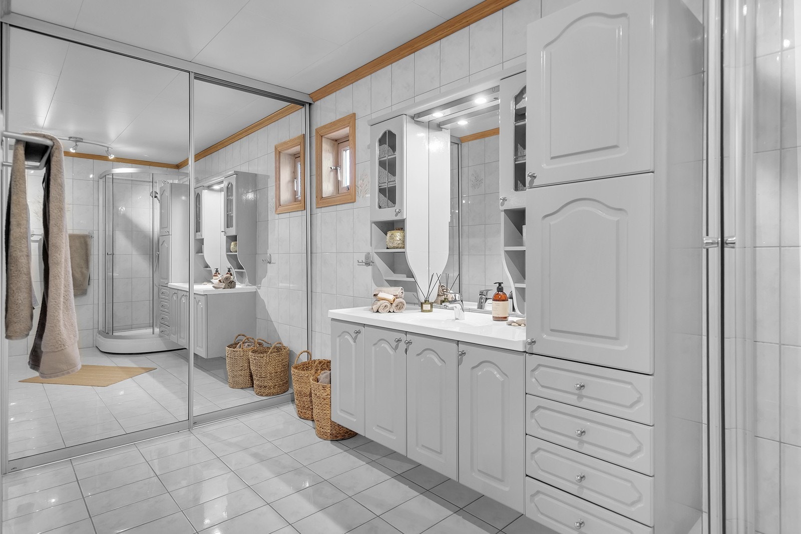 Stort bad med opplegg for vaskemaskin bak skyvedører Galleribilde