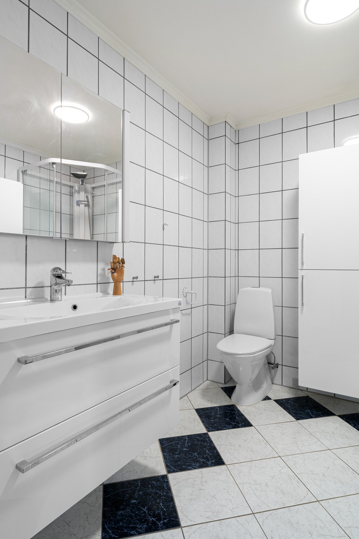 Den øvrige baderomsinnredningen består av hvite underskap med servant, speil og to matchende høyskap. Det er også opplegg for vaskemaskin på badet. Galleribilde