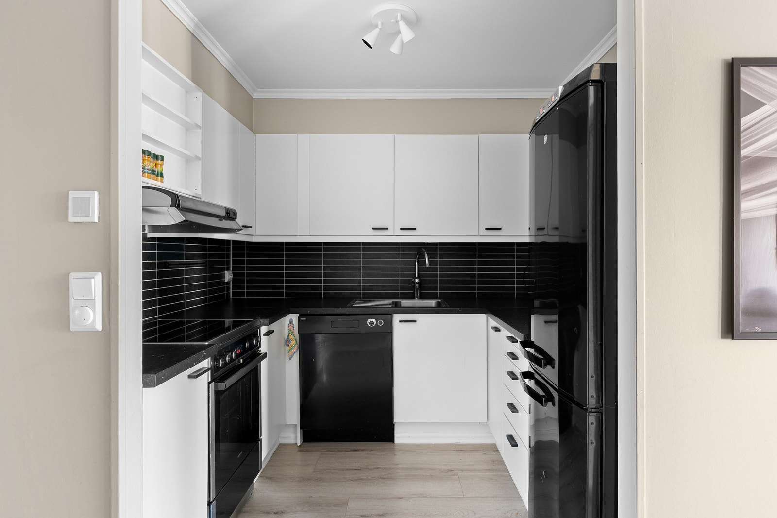 Innredningen har hvite, slette fronter og mørk benkeplate i laminat. Galleribilde