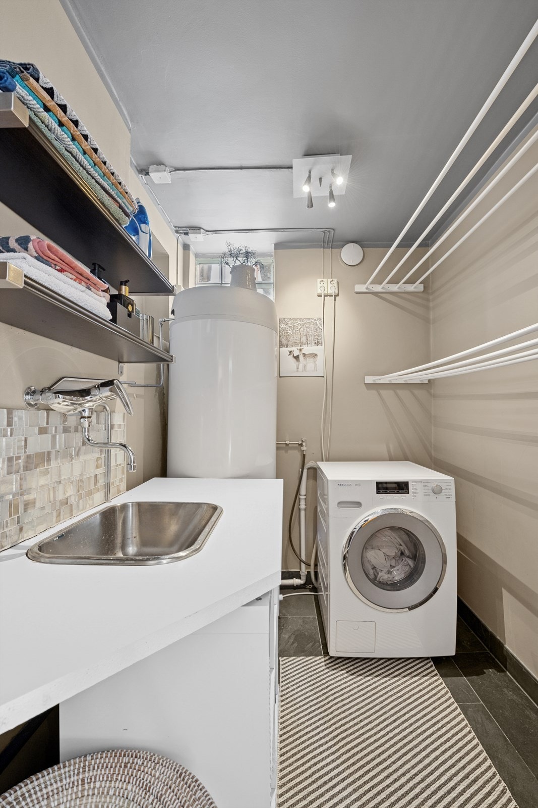 Vaskerom med innredning med nedfelt kum i rustfrittstål og opplegg for vaskemaskin. Friskluftventil på yttervegg. Galleribilde