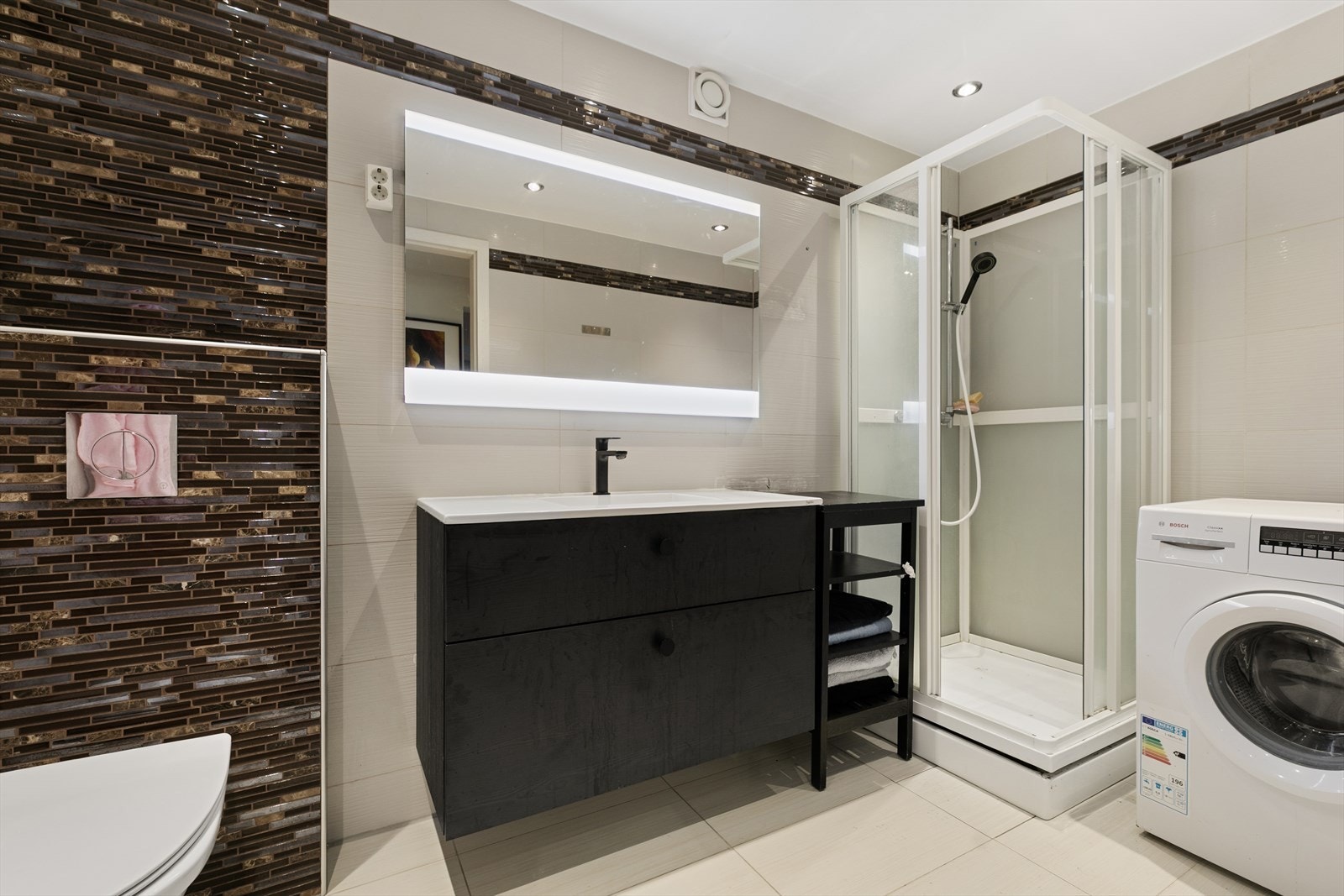 Badet på 3,25 m² er helfliset og har vegghengt toalett, dusjkabinett og opplegg for vaskemaskin. Nytt baderomsinnredning Galleribilde