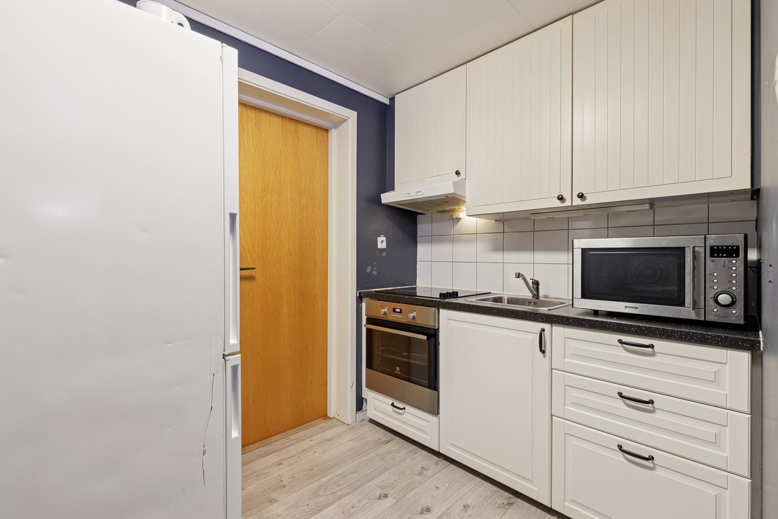 Kjøkkenet i hybeldelen har en lys innredning med profilerte fronter og en benkeplate med oppvaskkum og kjøkkenkran. Galleribilde