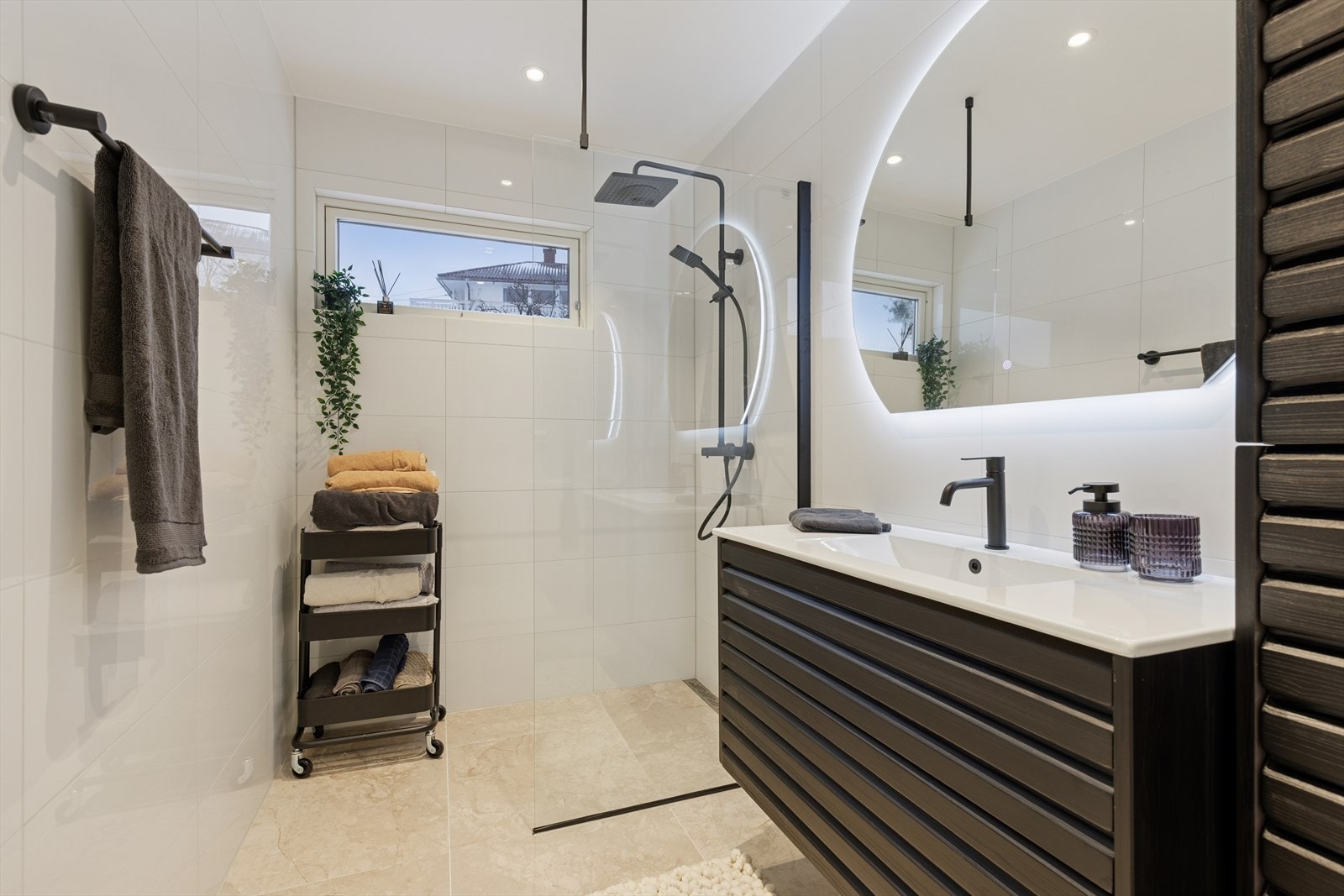 Delikat og moderne baderom med innfelte downlights i himlingen, dusj rett på gulv og en stilfull servantinnredning. Speil med integrert belysning over servanten gir et helhetlig og eksklusivt uttrykk. Galleribilde