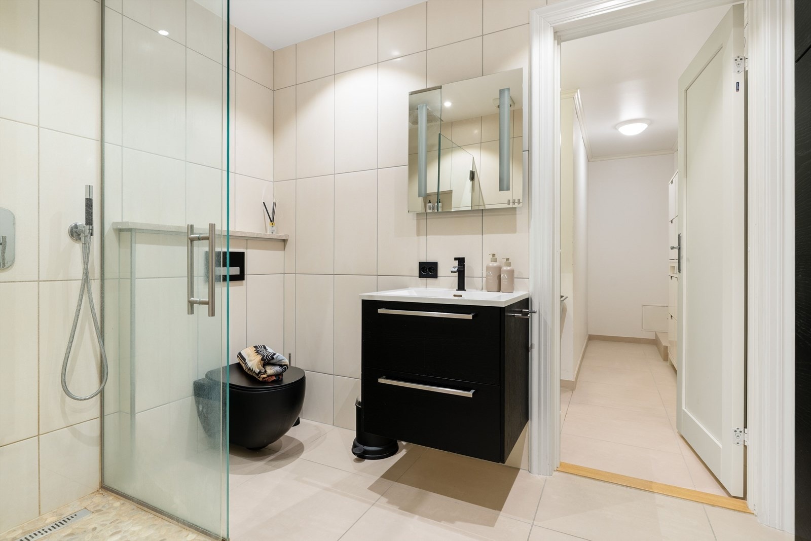 Flislagt baderom med behagelig gullvarme, servant, vegghengt toalett og dusjhjørnet med innfellbare glassdører for optimal arealutnyttelse. Galleribilde