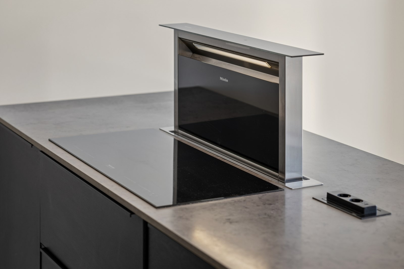 Koketoppen er elegant integrert i kjøkkenøya, som også har en innebygd avtrekksvifte for effektiv og stilren ventilasjon. Galleribilde