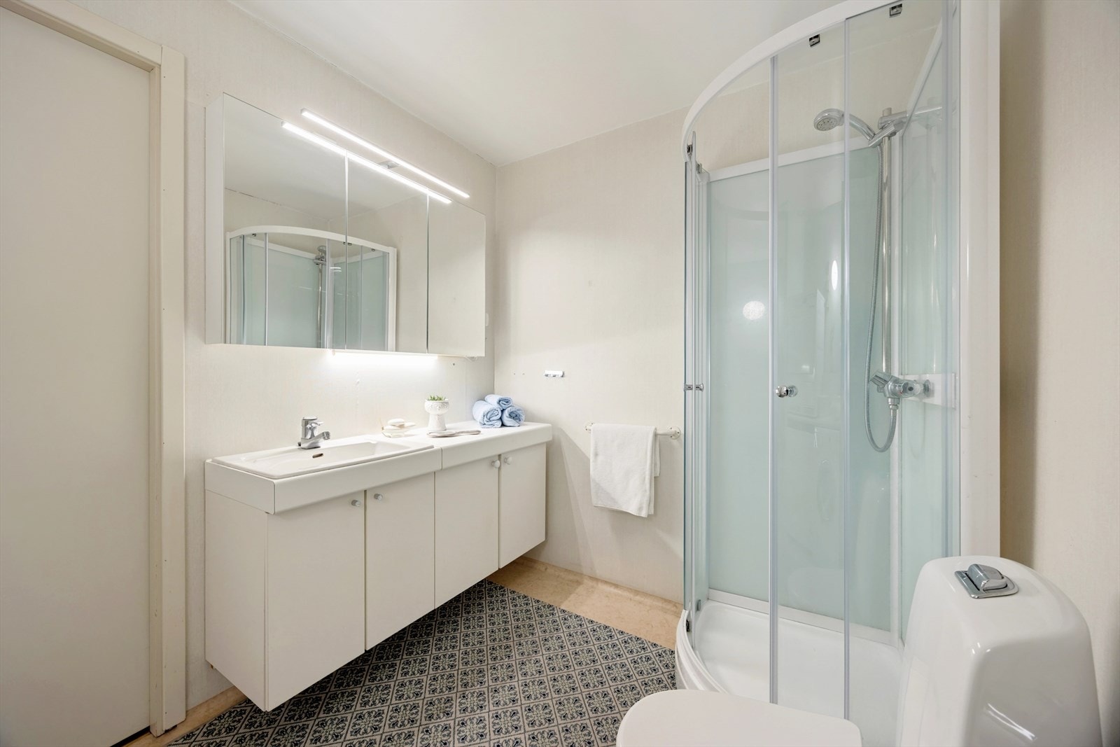 Badet har romslig servantskap og moderne speilskap med oppbevaring. Toalett og dusjkabinett av nyere dato Galleribilde