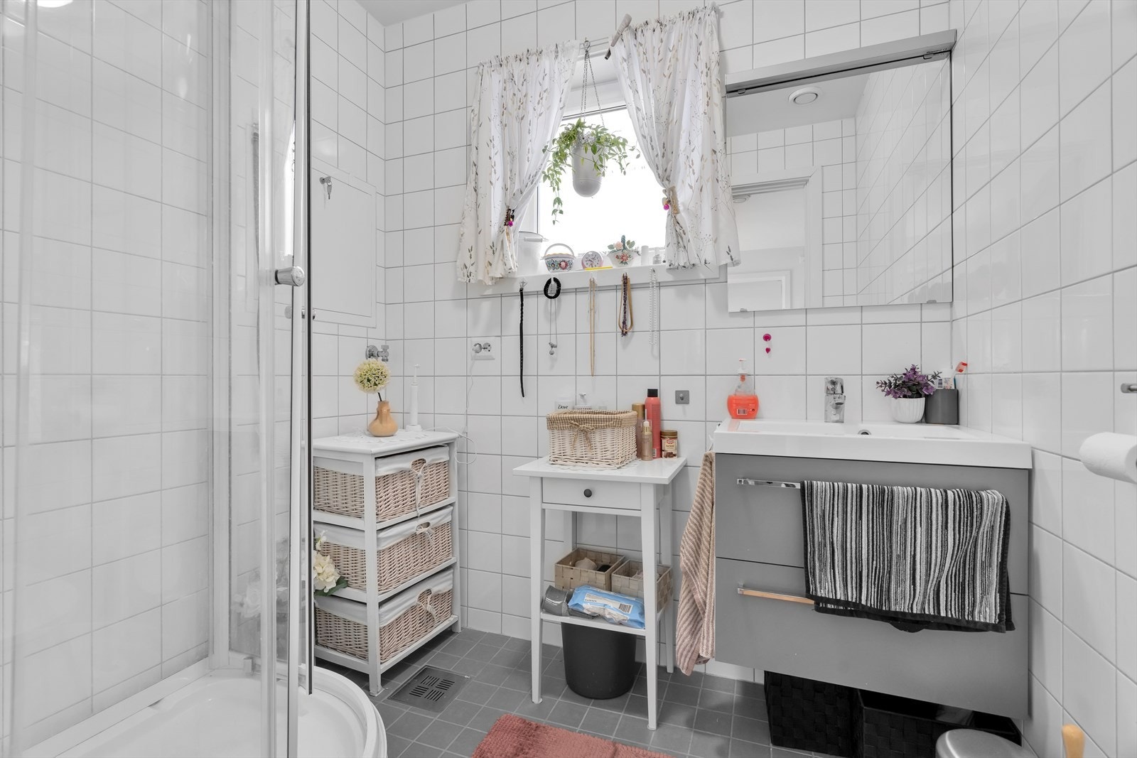 Badet er utstyrt med toalett, et praktisk baderomsmøbel med servant og et dusjkabinett Galleribilde