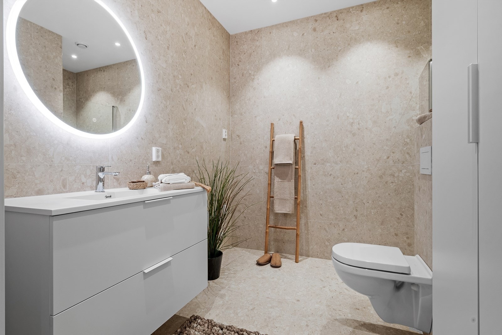 Badet har flislagte vegger og gulv med varmekabler, vegghengt wc, tidløs innredning og dusjhjørne. Det er i tillegg opplegg for vaskemaskin på badet. Galleribilde