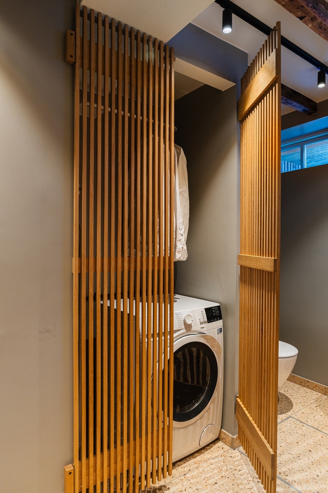 Bak spiledører i tre er det praktisk opplegg for vaskemaskin. Galleribilde