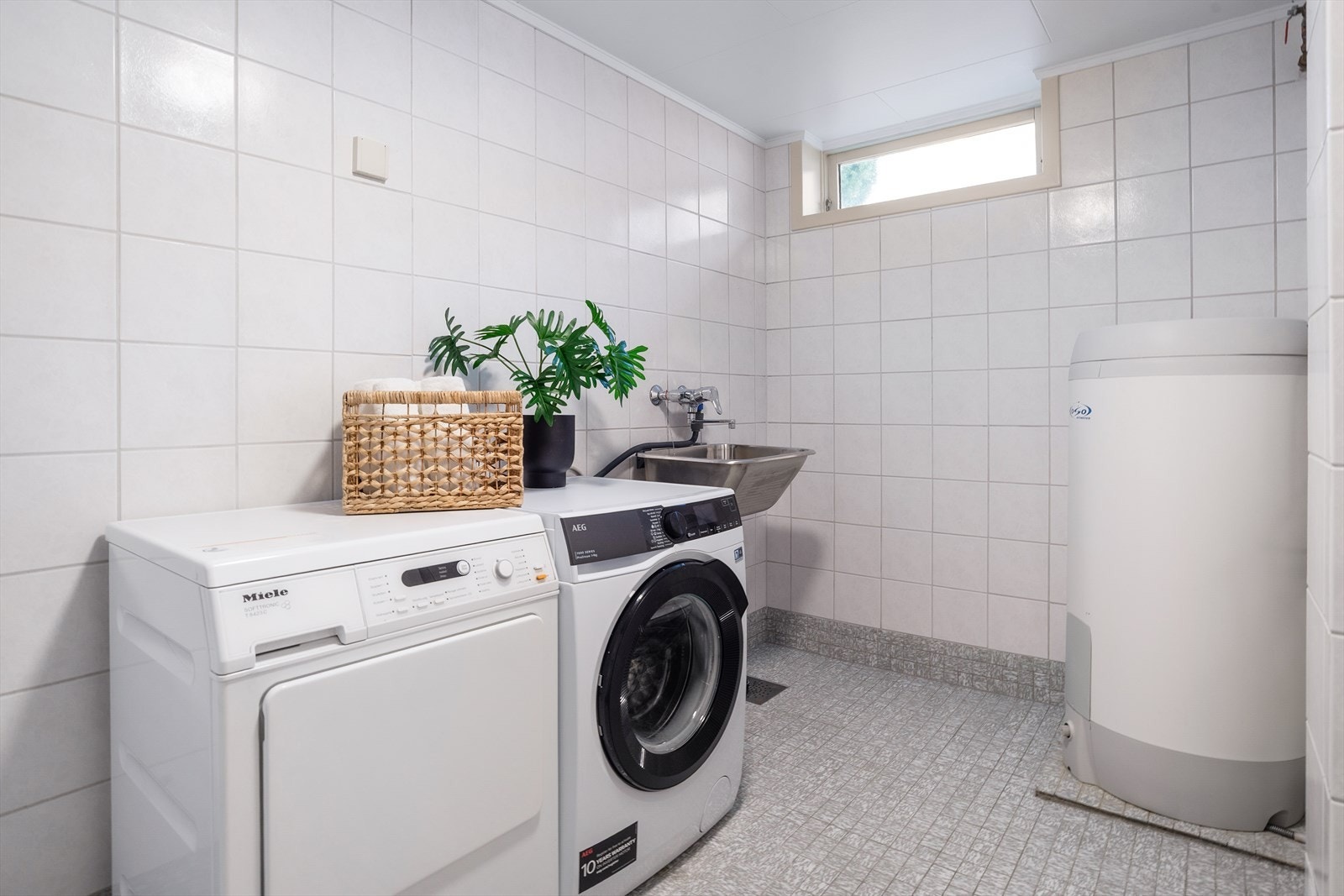 Boligen har et separat vaskerom i kjelleretasjen. Rommet er innredet med vaskekum i stål med ettgreps blandingsbatteri samt opplegg for vaskemaskin og tørketrommel. Vaskerommet har fliser på både gulv og vegger. Galleribilde