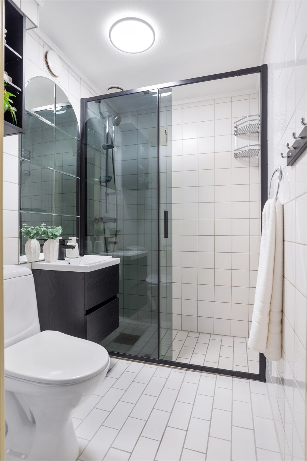 Eldre bad i kjelleretasjen med flislagte overflater. Oppgradert ned nytt servantskap, servant og blandebatteri i 2026, samt dusjveggen fra 2025. Galleribilde