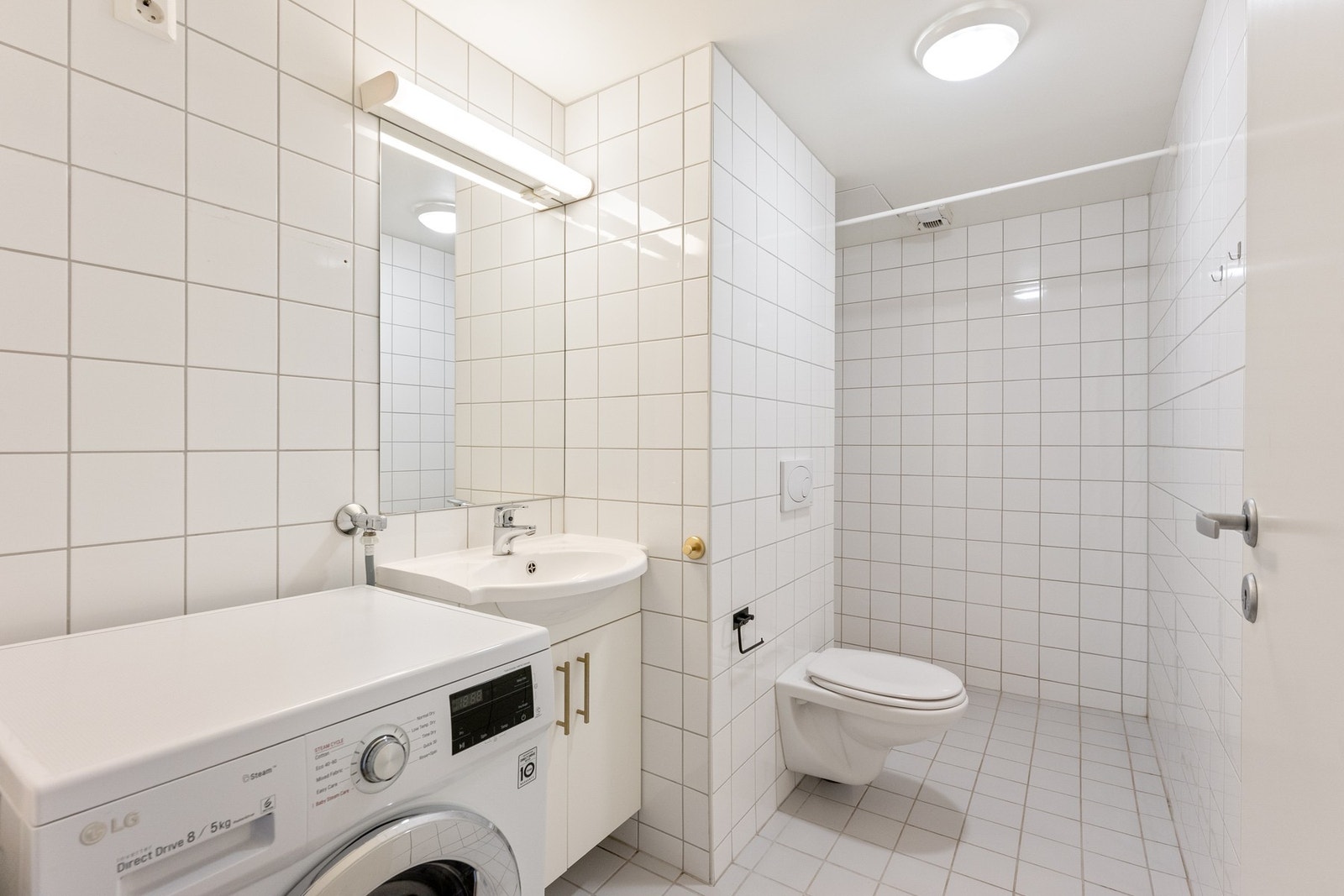 Flislagt bad med varmekabler i gulv og opplegg for vaskemaskin. Galleribilde