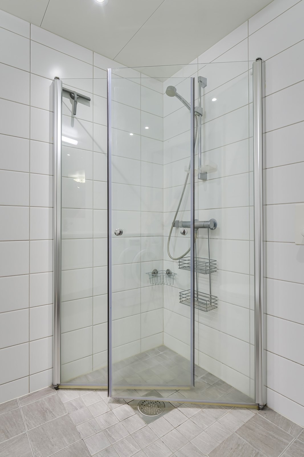 Innredningen består av servantskap, veggmontert toalett,opplegg for vaskemaskin og dusjsone med svingdører i glass. Galleribilde