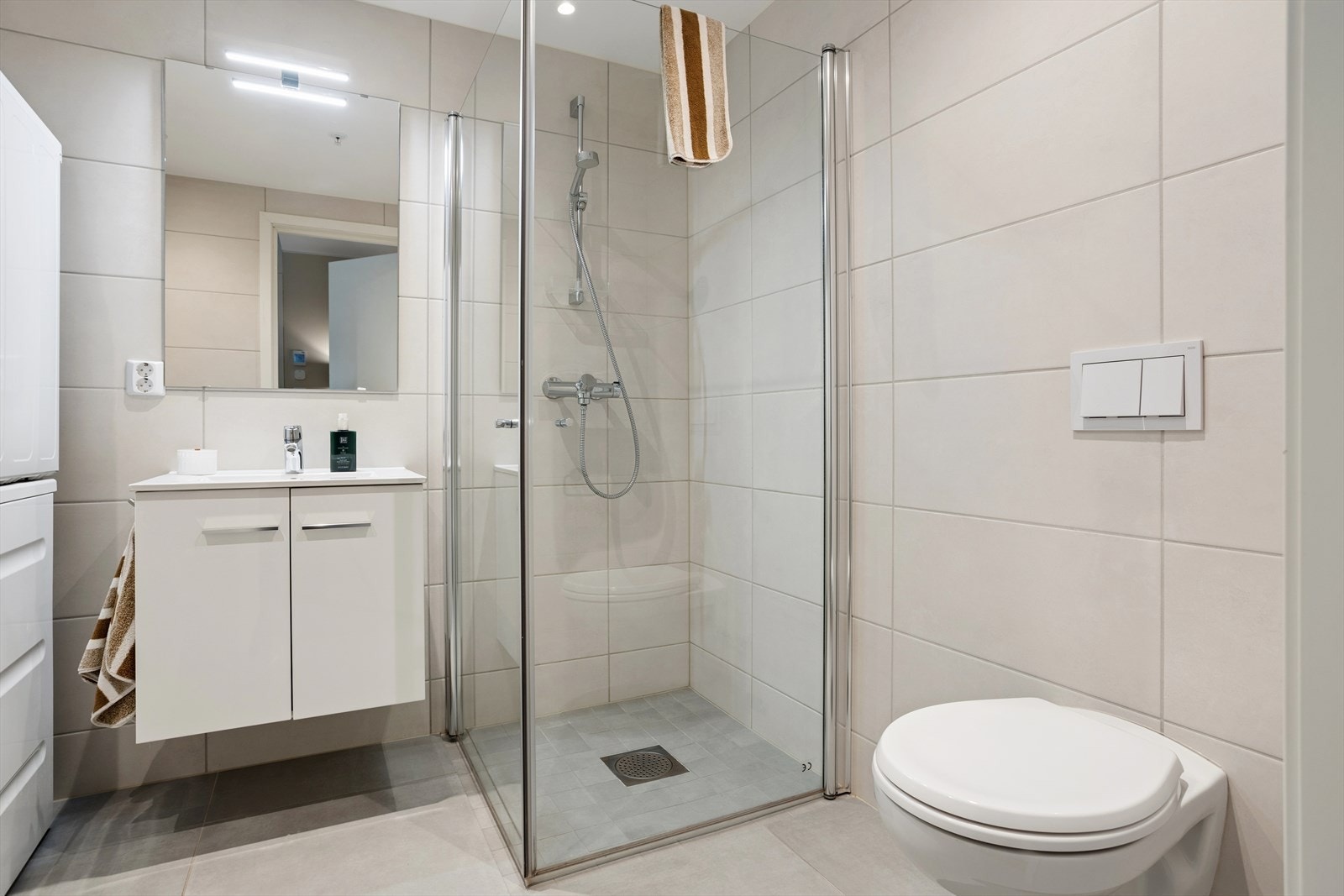 Badet er utstyrt med opplegg for vaskemaskin, servant med innredning, dusj og vegghengt toalett. Galleribilde