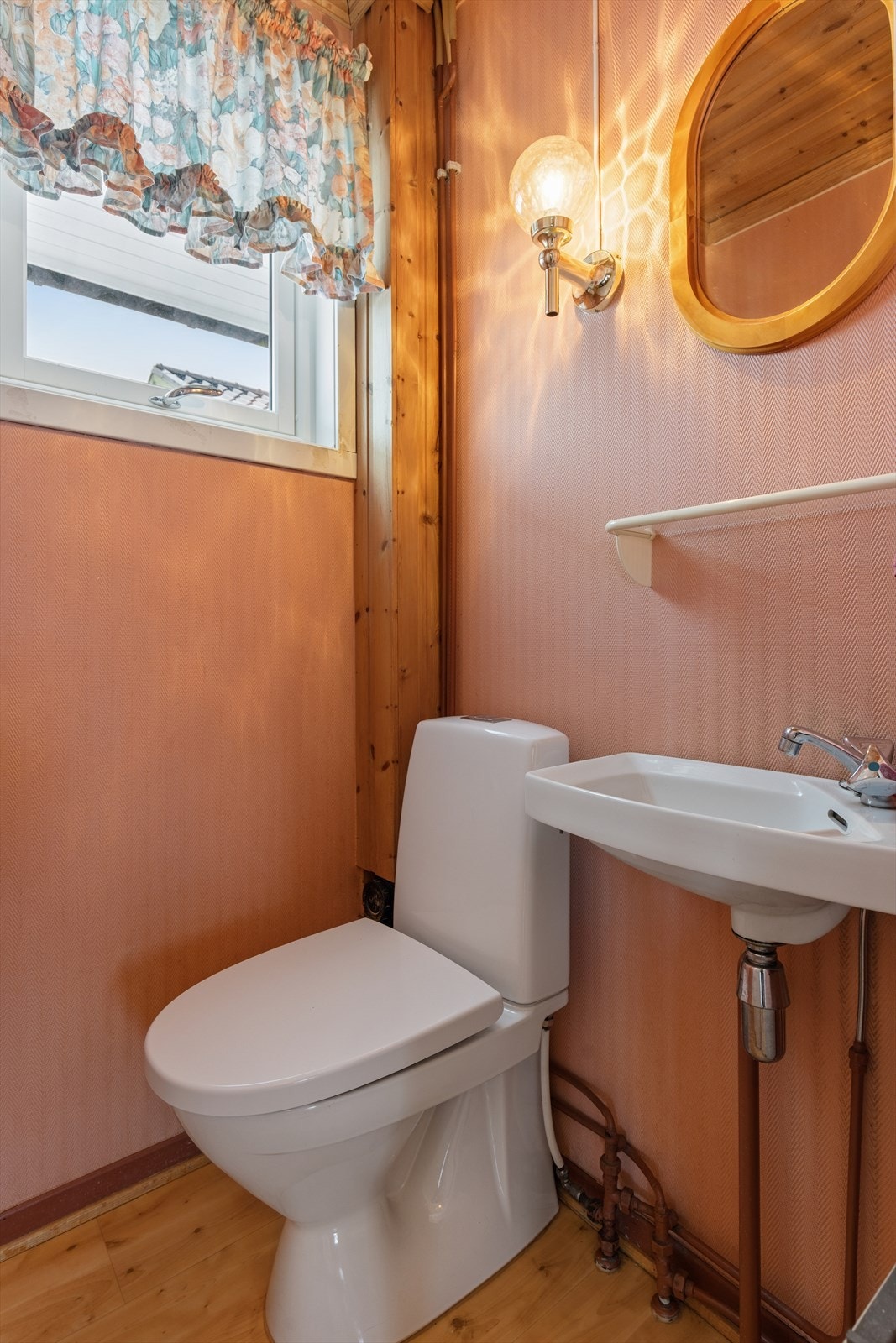 Separt toalettrom med tapet på vegger og belegg på gulv og panelovn som oppvarmingskilde. Innredet med servant og wc. Galleribilde