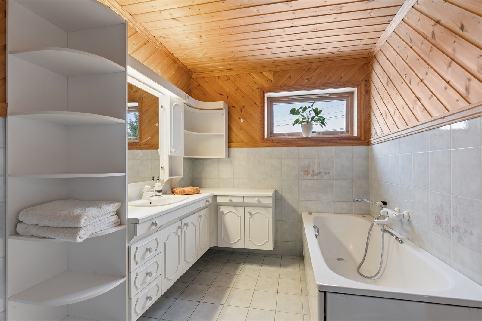 Bad med delvis flislagte vegger og fliser på gulv. adet er Innredet med badekar, dusjhjørne og badekar. Galleribilde