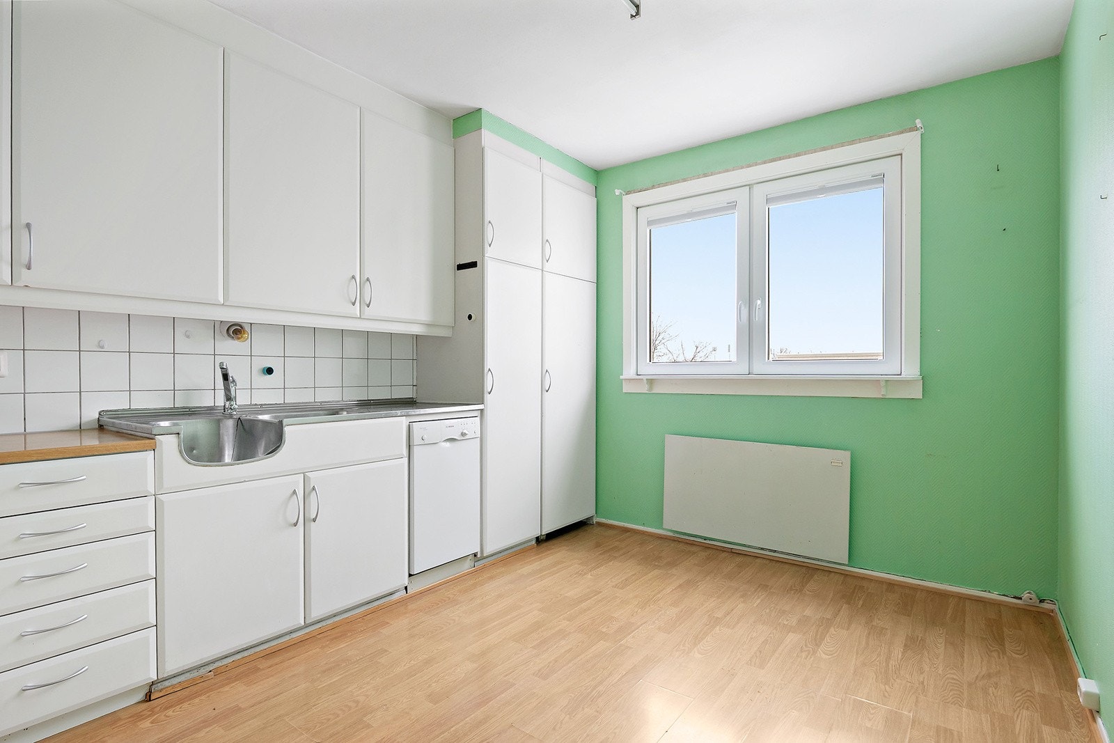 Separat kjøkken med en innredning bestående av originale skapskrog, slette fabrikklakkerte fronter og laminat benkeplate. Galleribilde