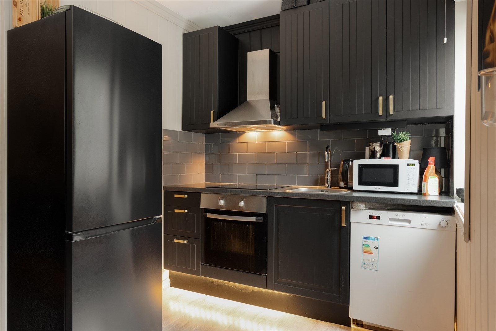 Kjøkkenet er innredet med laminerte benkeplater, nedfelt stålvask, profilerte fronter og opplegg for oppvaskmaskin. Det er også integrert platetopp og stekeovn. Galleribilde