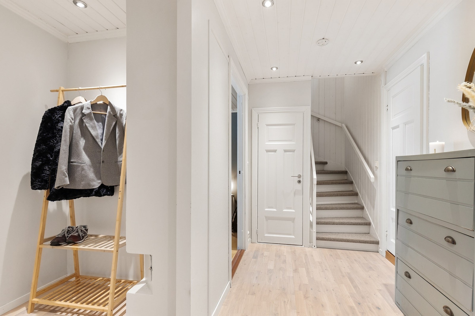 Entréen i underetasjen har flislagt gulv, downlights og nylagte gulv i tilstøtende gang. Under trappen er det rikelig en romslig bod, med montert lys og mange knaggrekker, slik den kan både brukes til garderobe og lagring/oppbevaring. Galleribilde