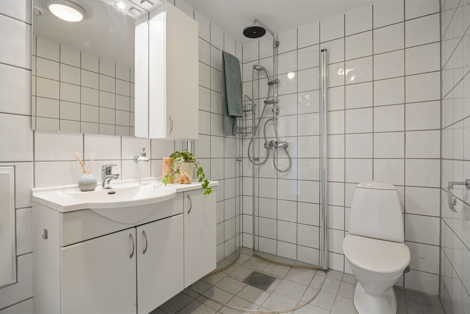 Badet på 4,5 m² er fra byggeåret og fremstår med tidløse, flislagte overflater som gir et rent og praktisk uttrykk. Dusjhjørne med glassvegger. Galleribilde