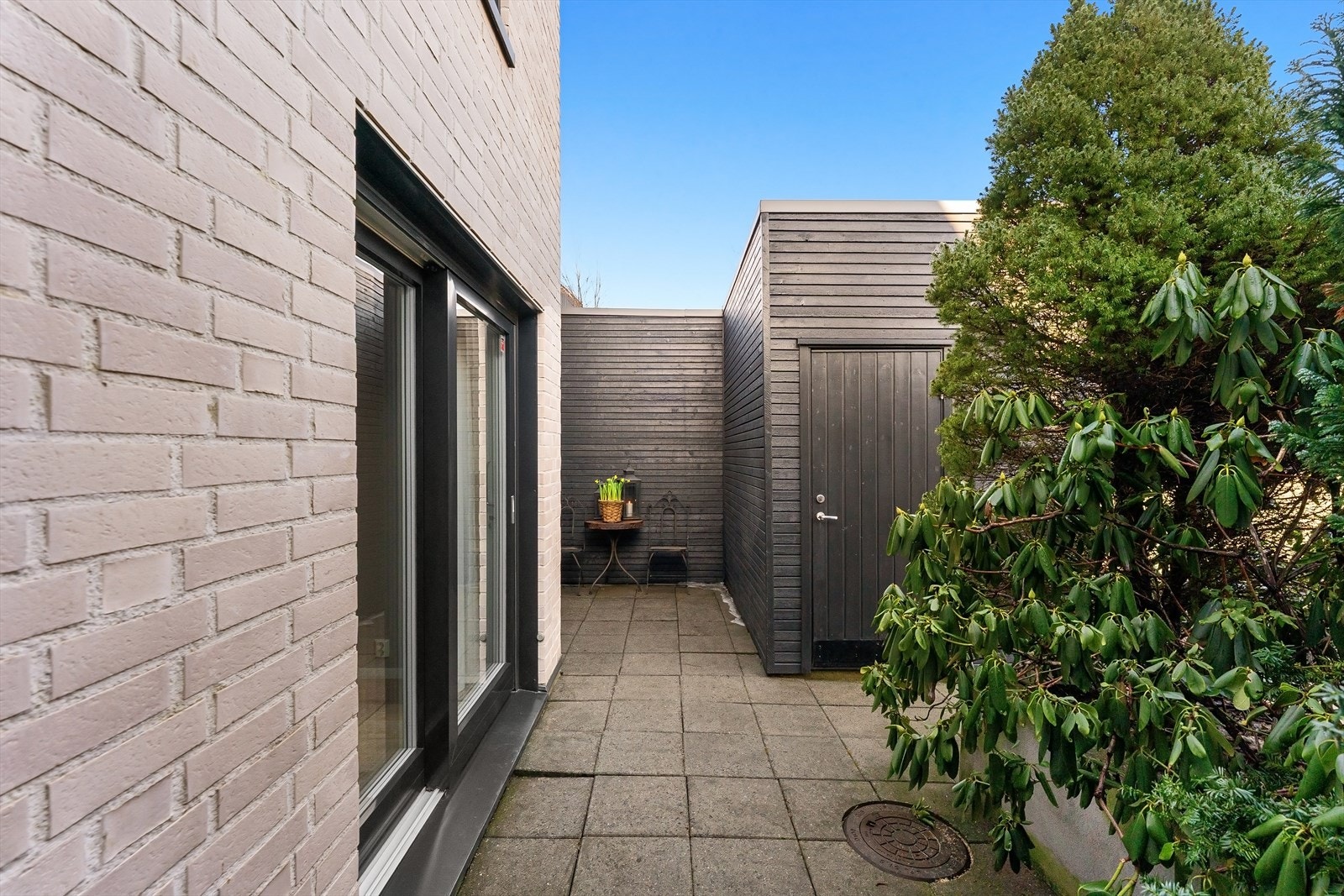 På husets forside finnes en uteplass, belantning, praktisk utebod og en carport med elbillader Galleribilde