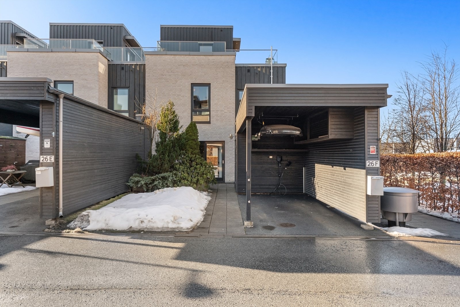 Inngangsparti og carport med elbilader. Det er også gjesteplasser lenger inn på feltet. Galleribilde