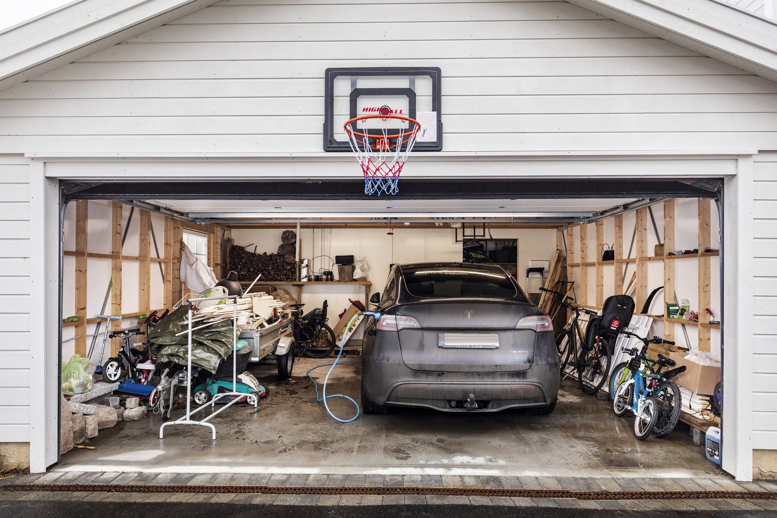 Dobbel garasje med sportsbod i bakkant av garasjen. Elbillader er montert Galleribilde