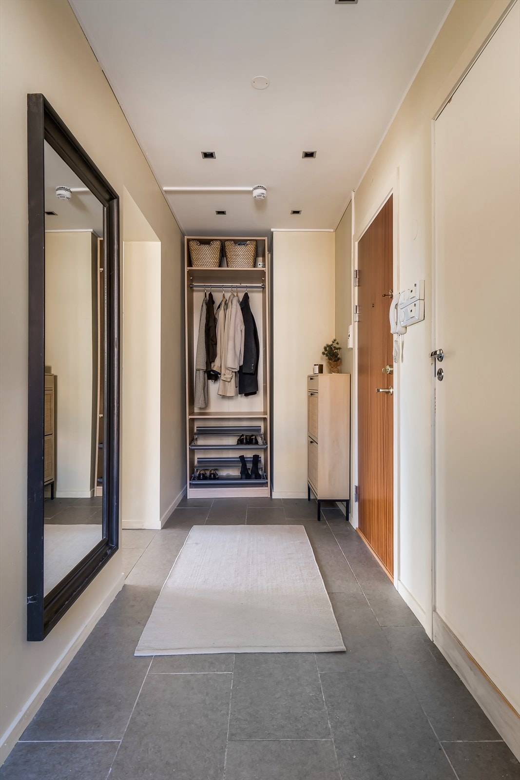 Det første som møter deg når du kommer inn i leiligheten er en lys og romslig gang med fliser på gulv og malte vegger. Det er dimbare downlights i gangen. Galleribilde