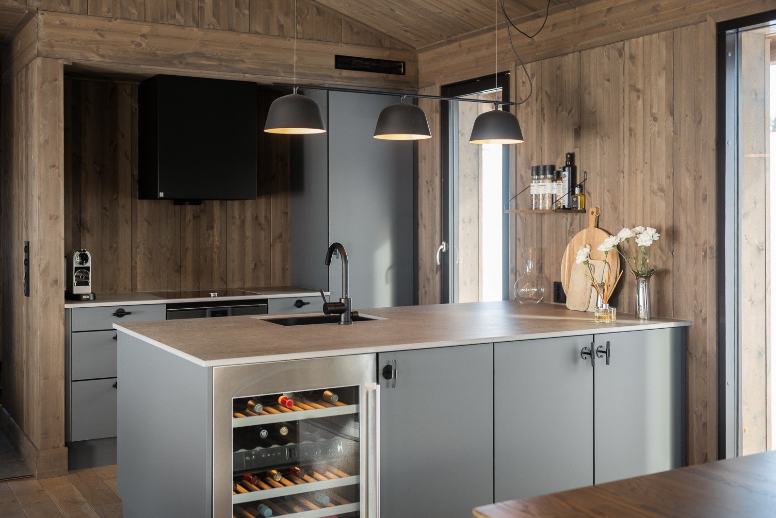 Kjøkkenøya har en solid Silestone Dekton benkeplate og integrert vinskap fra Gaggenau. Galleribilde