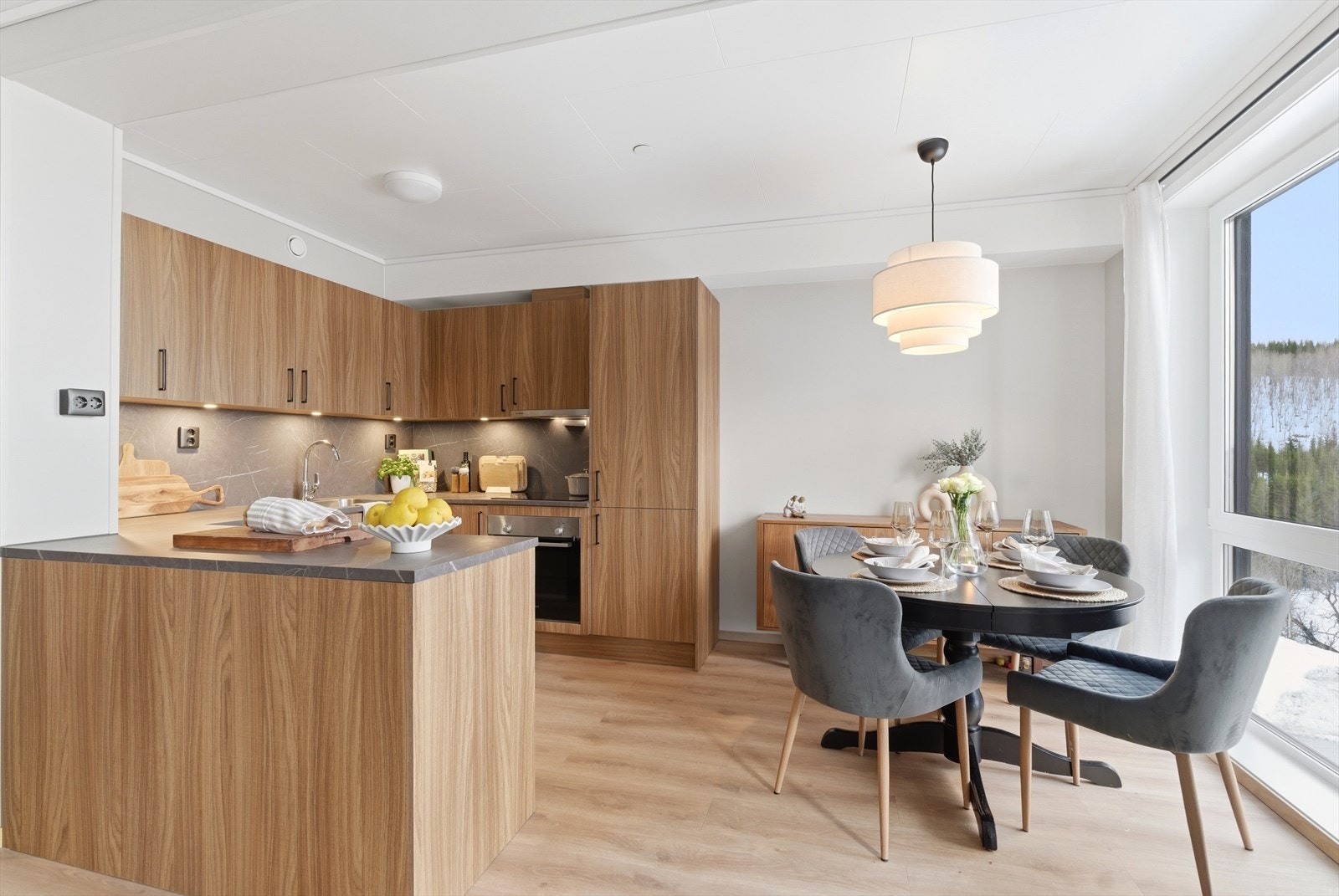 Denne leiligheten har gjennomtenkte stilvalg som kontrasterer den ellers lyse og delikate innrammingen, i form av mørkere kjøkken og benkeplate, og sorte dører og karmer. Galleribilde