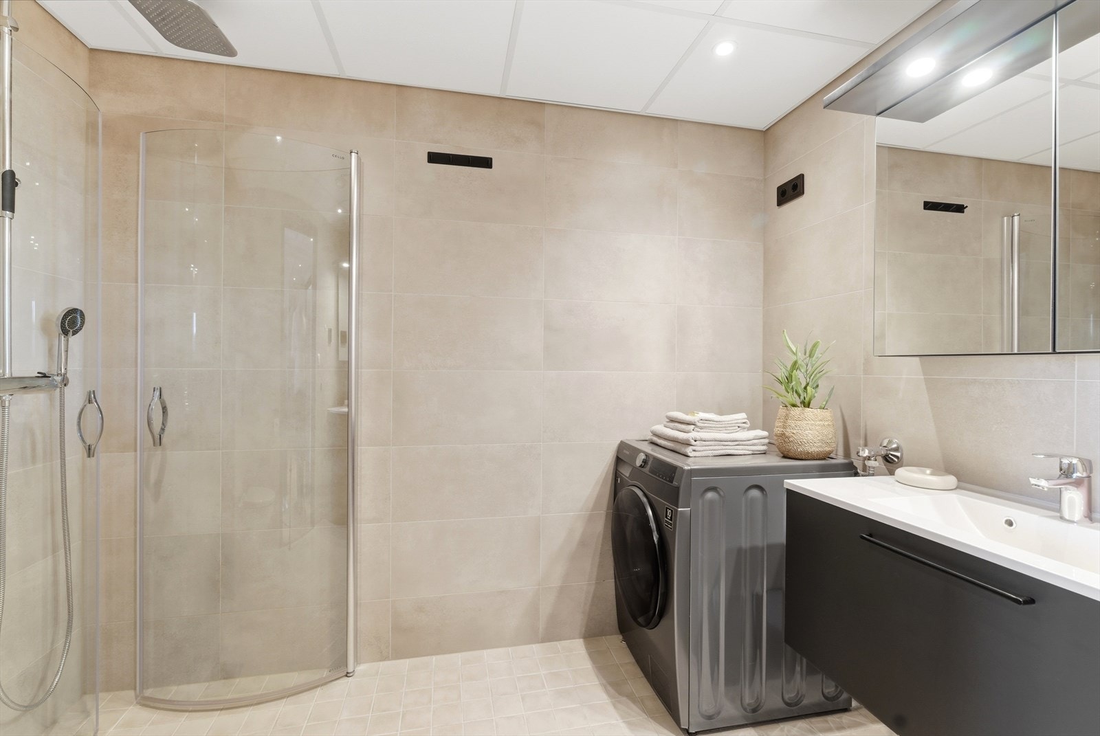 Baderommet har en moderne, stilren innredning, flislagt gulv med lun gulvvarme, innfelt spotbelysning i tak, og innfellbare dusjdører i glass. Galleribilde