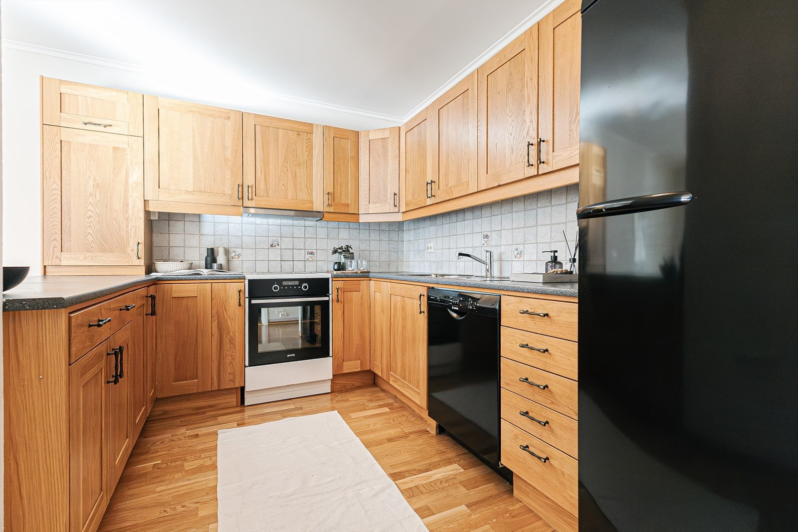 Flislagt mellom over- og underskap gir en praktisk arbeidsflate på kjøkkenet Galleribilde