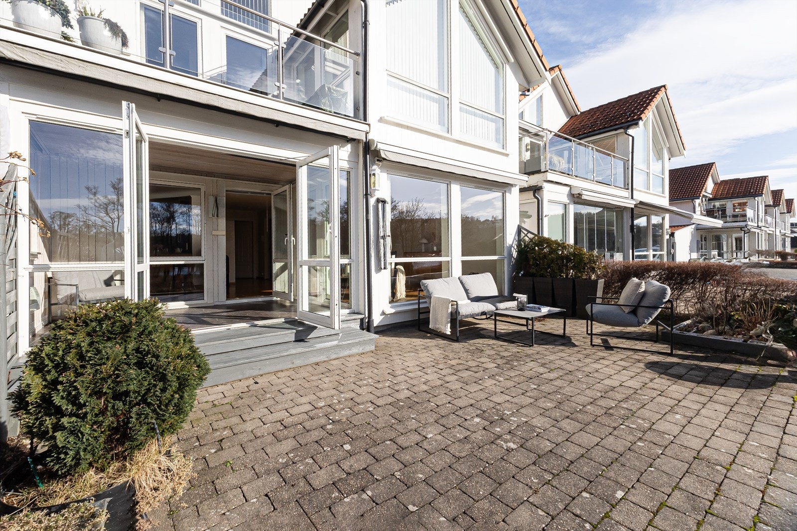 Innglassert terrasse gir beskyttelse mot vær og vind samtidig som den bevarer utsikten. Rundt hjørnet for hagemøblene er det utvendig bod Galleribilde