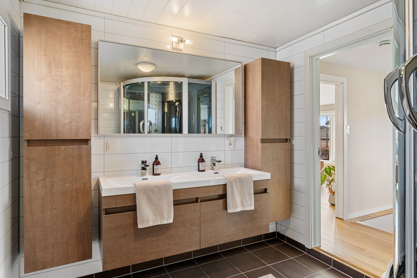 Badet er innredet med vegghengt wc, dusjkabinett og pen dobbel seksjon med vask, samt vegghengte oppbevaringsskap Galleribilde