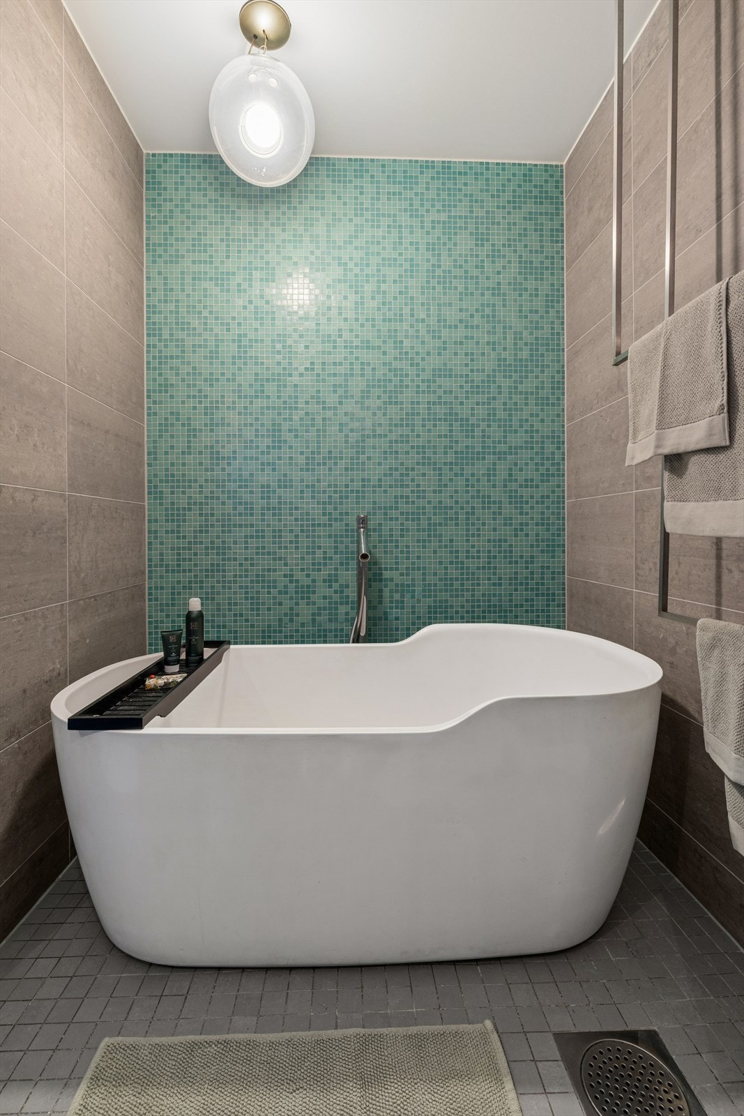 Lekkert frittstående badekar av modellen Funny West fra Antonio Lupi med mosaikkfliser fra Bisazza på kontrastvegg. Galleribilde