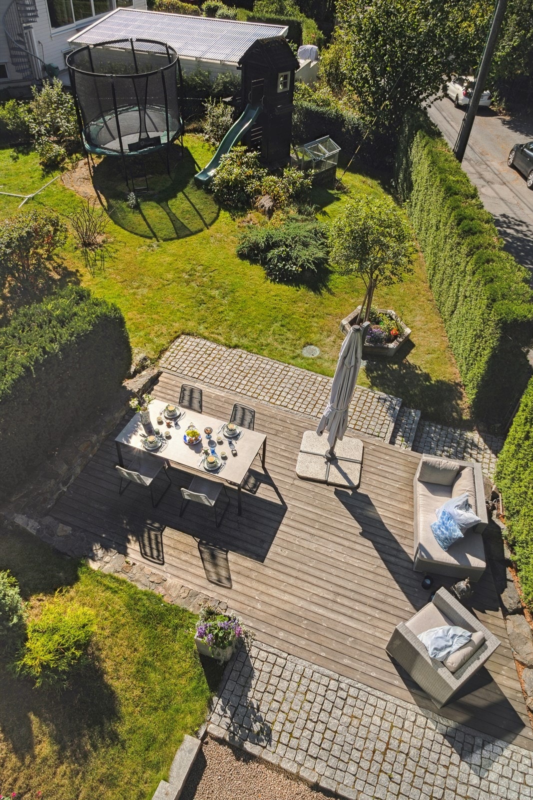Hagen er pent opparbeidet med markterrasse, plen, blomster og lekehus med sklie Galleribilde