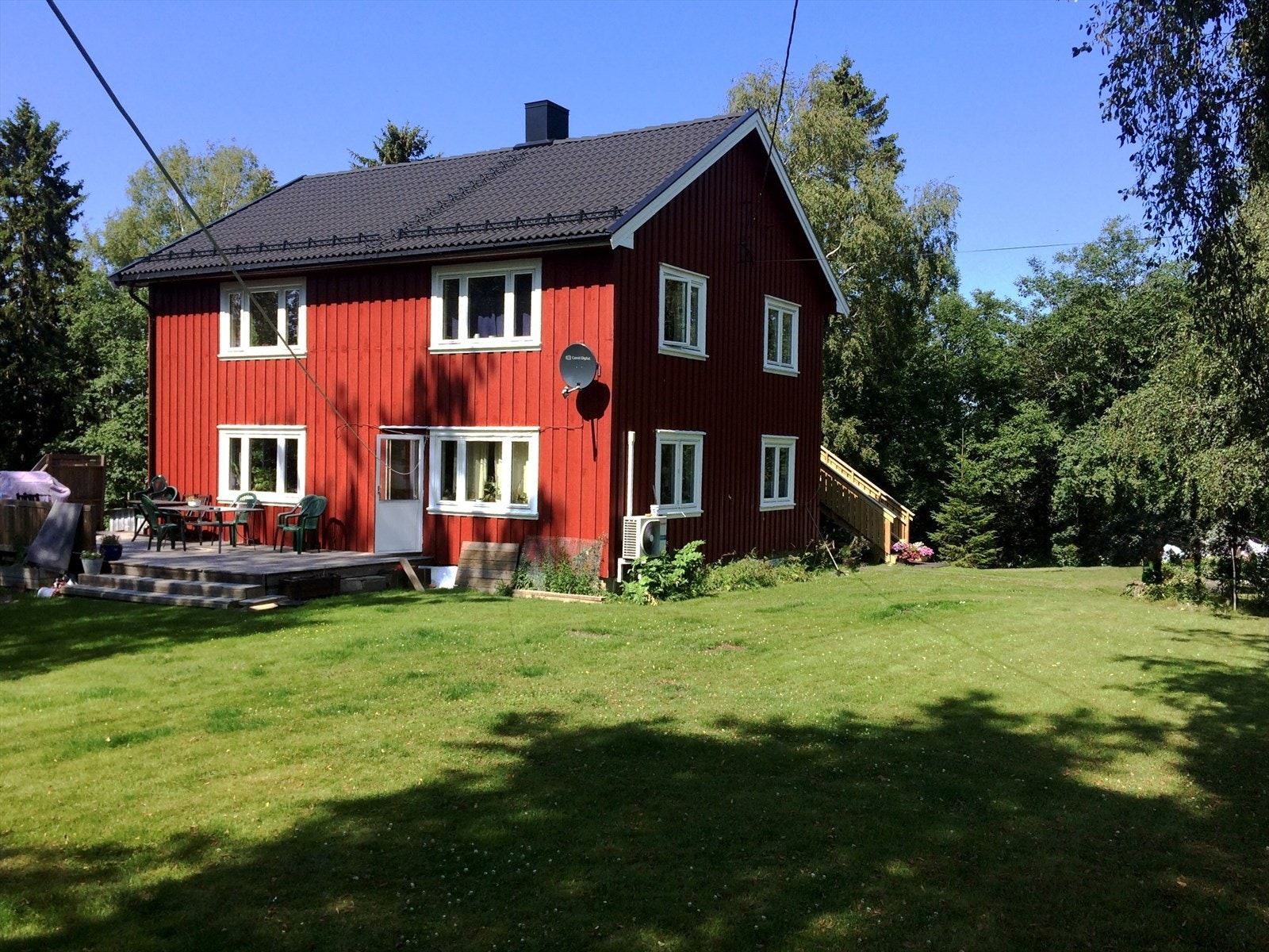 Sommerbilde. Det er adkomst fra stuen terrassen videre via trapp til hagen. Galleribilde