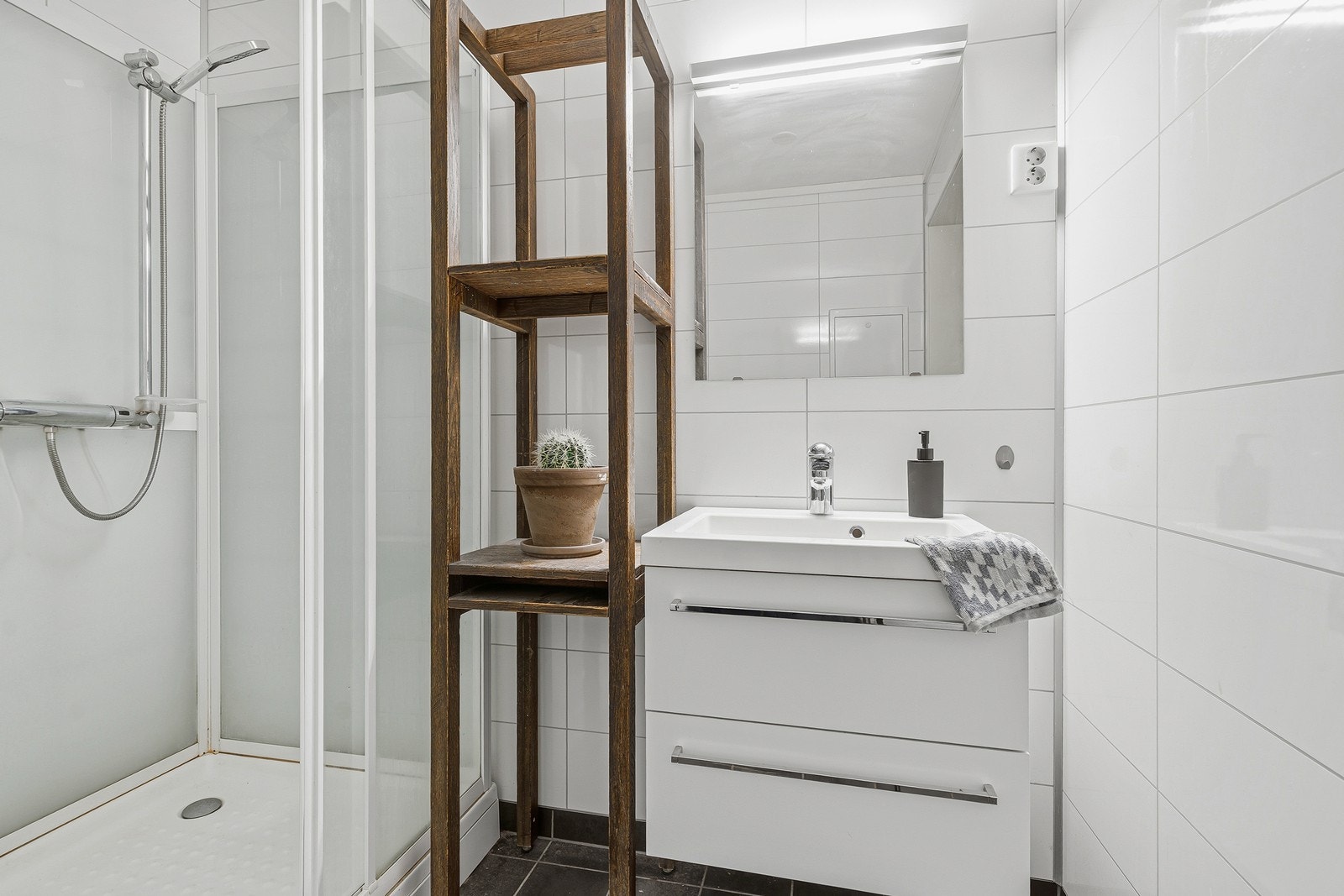 Badet er innredet med nedfelt servant, toalett, dusjkabinett og opplegg for vaskemaskin Galleribilde