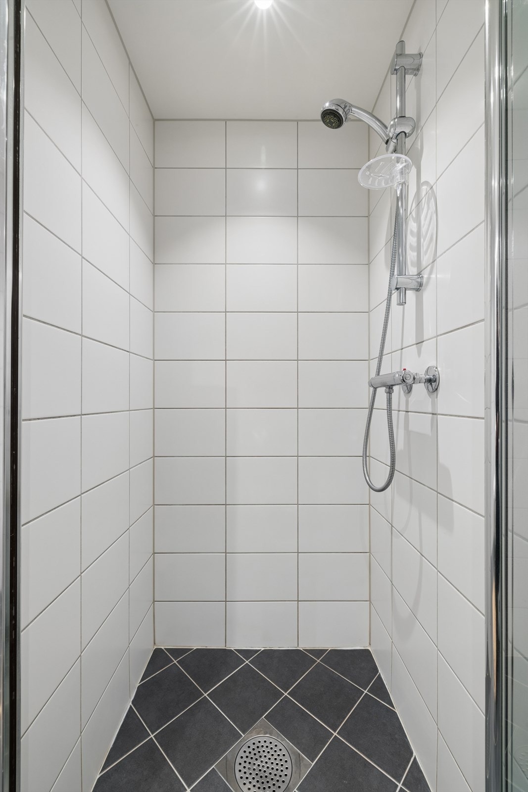 Baderom med dusjhjørne med innfellbare dører og elektriske varmekabler i gulvet for ekstra komfort. Galleribilde