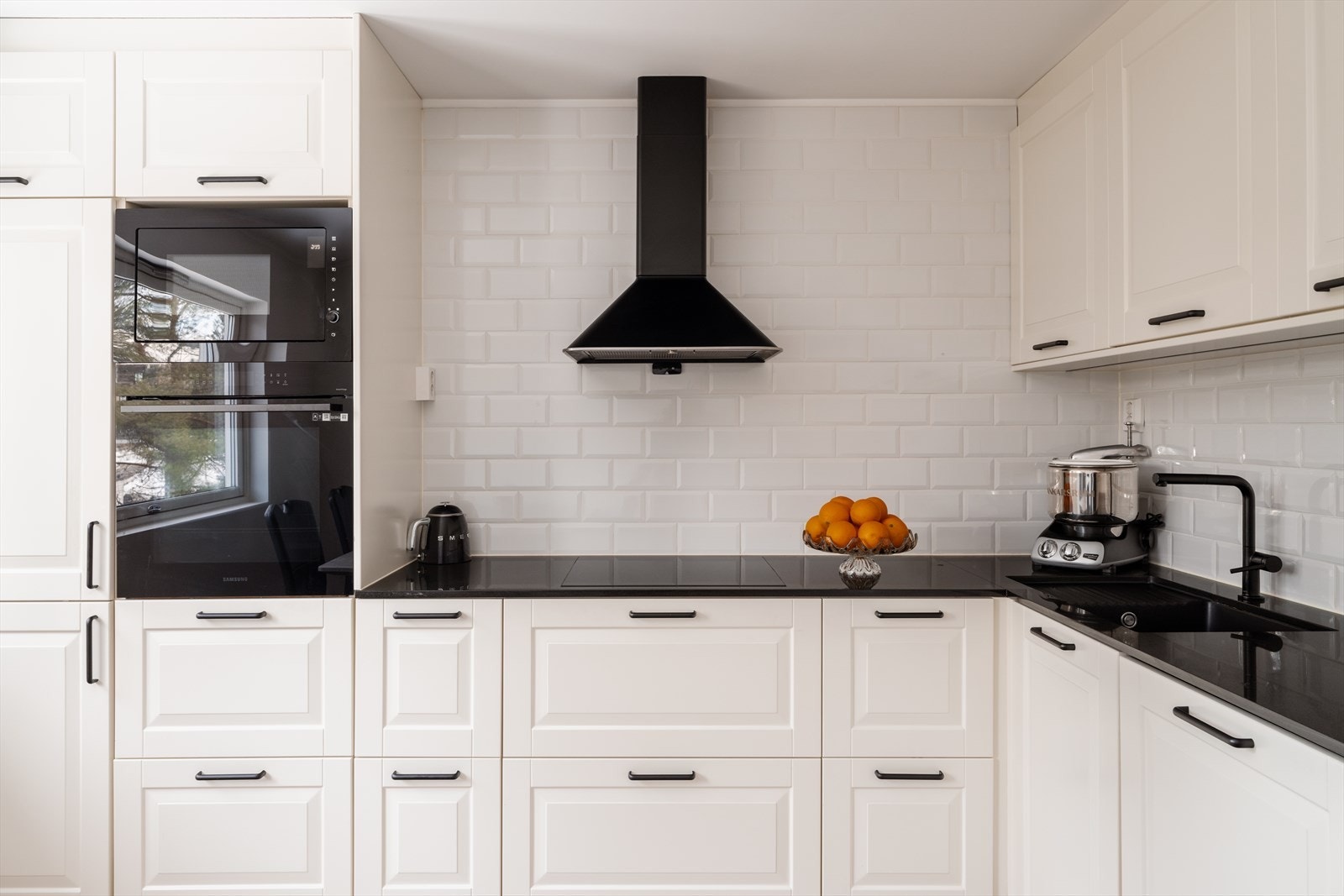 Kjøkkenet har mørk komposittbenkeplate og fliser mellom benk og overskap. Galleribilde