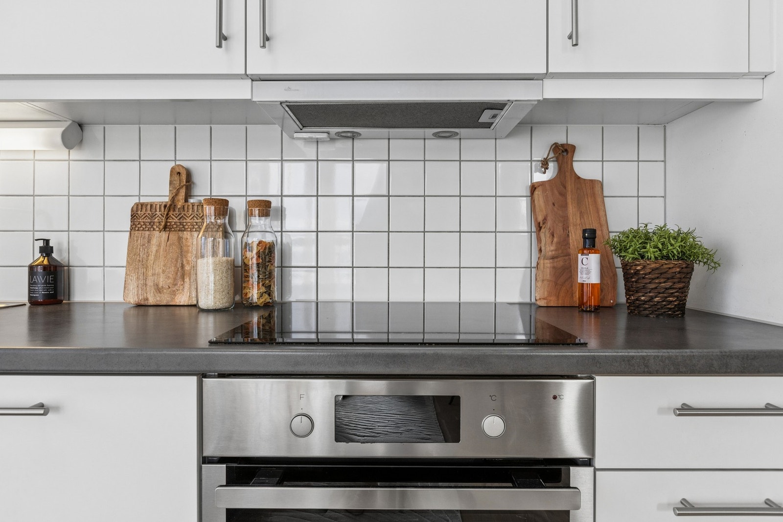 Kjøkken med hvite glatte fronter og god arbeidsplass. Kjøkkenet har integrert koketopp og komfyr, kjøleskap og oppvaskmaskin. Galleribilde