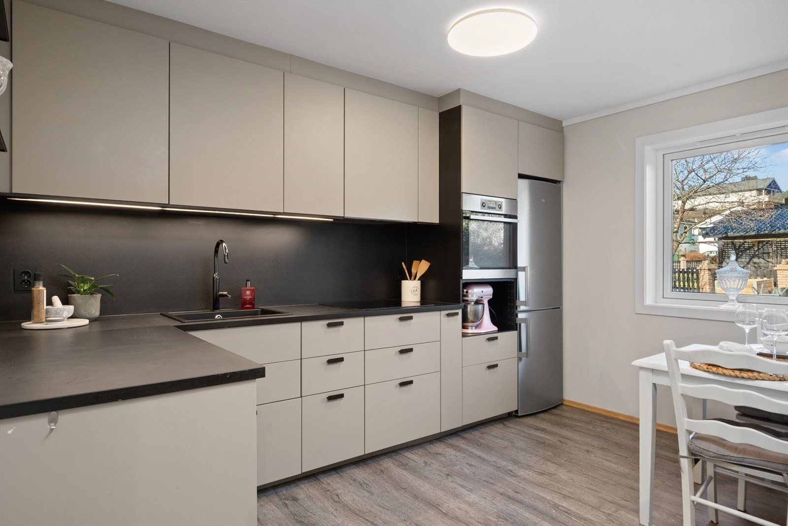 Delikat kjøkkeninnredning med moderne beige, slette fronter og benkeplate av laminat. Galleribilde