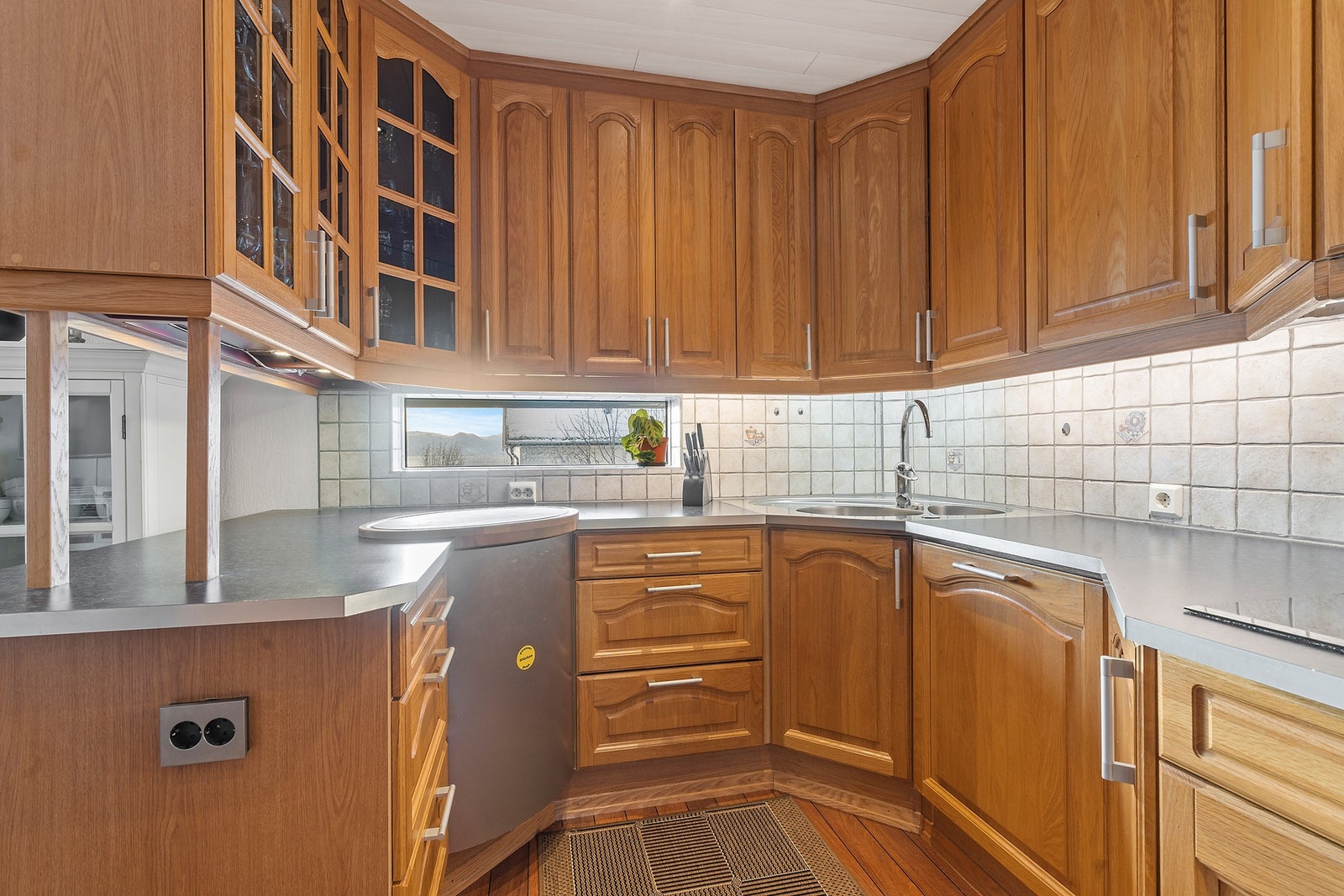 Hjørneløsningen utnytter plassen effektivt, med et praktisk vindu over arbeidsbenken. Galleribilde