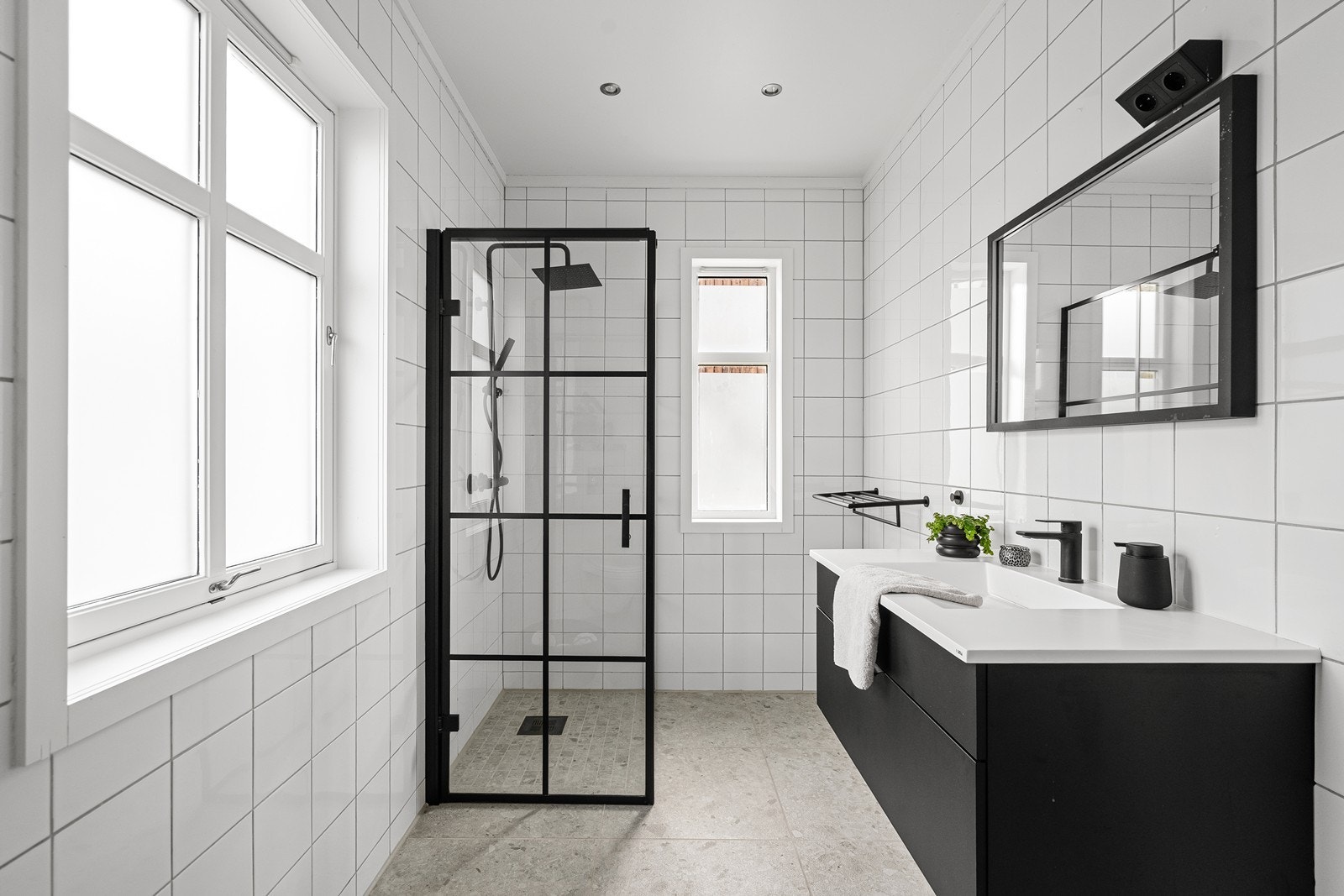 Hellfliset bad i 1. etasje med sort baderomsinnredning. Spotter i tak Galleribilde