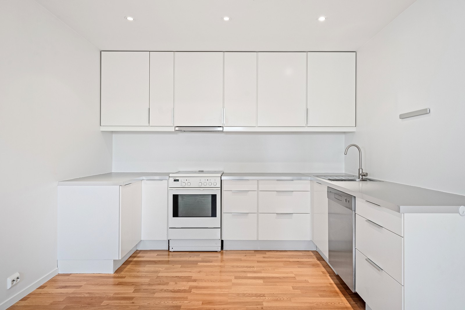 Kjøkken med hvite fronter samt god skap og benkeplass Galleribilde