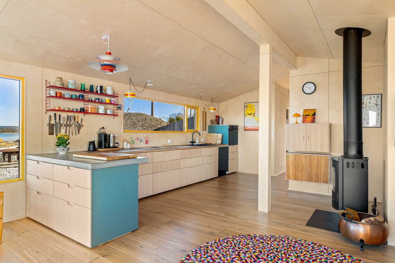 Kjøkkeninnredningen er moderne i sitt formspråk, åpne hyller og et panoramavindu er satt inn istedenfor overskap. Galleribilde