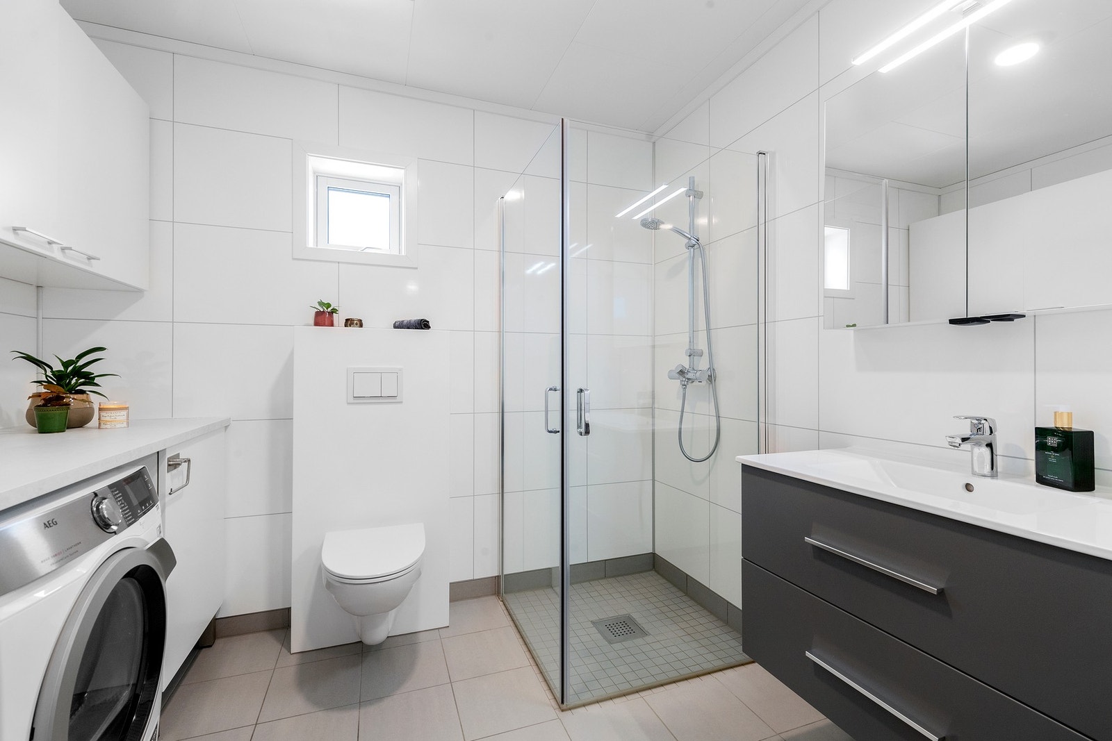 Lyst og romslig bad/vaskerom med flotte baderomsplater på vegg og flis på gulv. Galleribilde