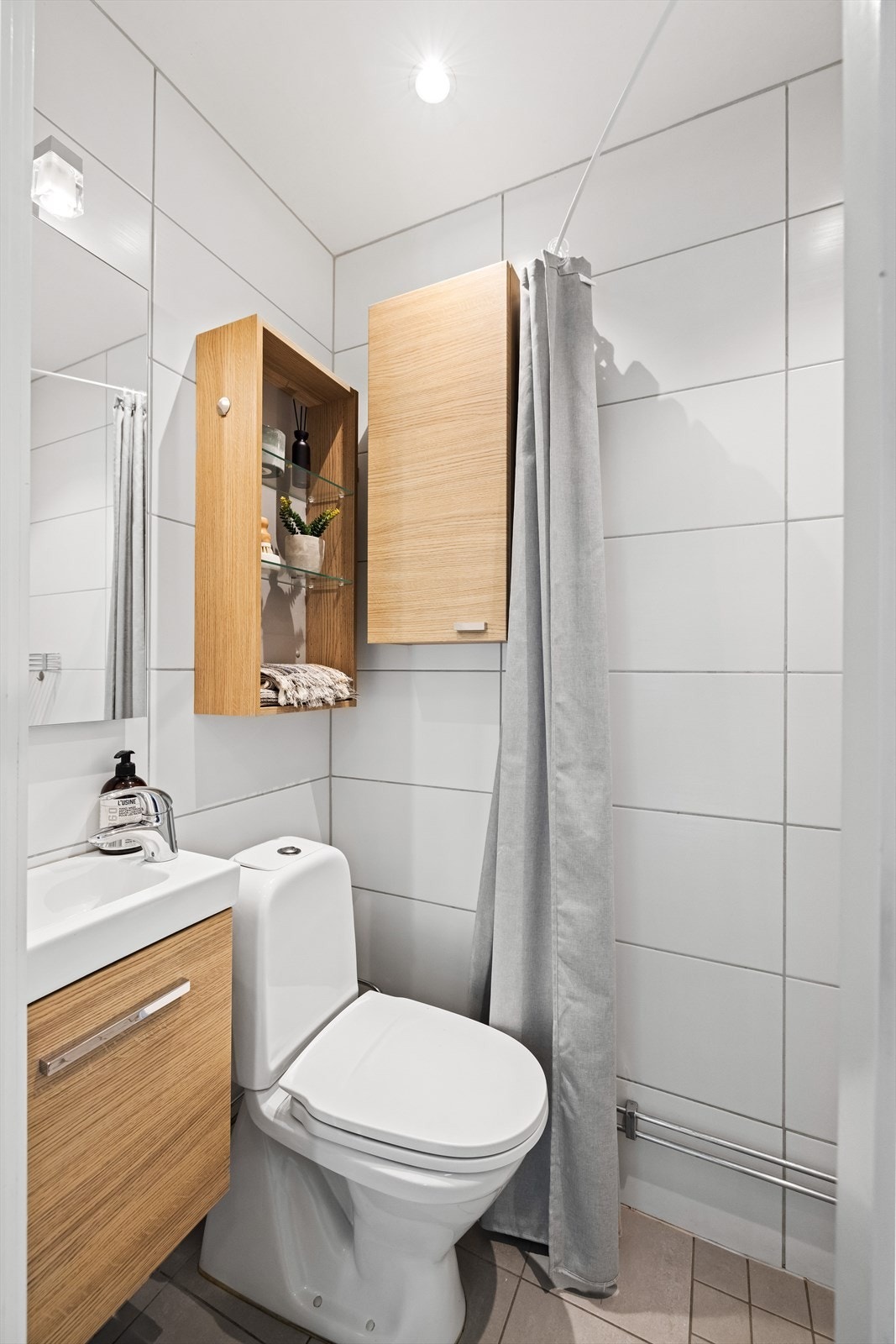 Badet er flislagt og innredet med servant, speilskap og toalett. Galleribilde